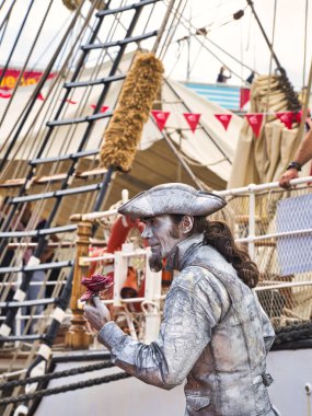 ROUEN, FRANCE - June Circa, 2019. Tanımlanamayan boyanmış pandomimci adam sokakta donuk heykelini gösteriyor. Donanma toplantısı için Rouen rıhtımındaki yelkenlinin yakınında.