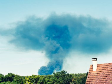 Yanan bir plastik geri dönüşüm yeri, gökyüzü mavi yaz gününde koyu siyah bir duman yığınına neden olur. Tehlike, keder. Terörist saldırı ya da patlama. Çevre felaketi