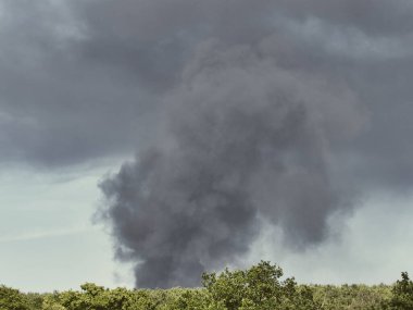 Yanan bir plastik geri dönüşüm yeri, gökyüzü mavi yaz gününde koyu siyah bir duman yığınına neden olur. Tehlike, keder. Terörist saldırı ya da patlama. Çevre felaketi