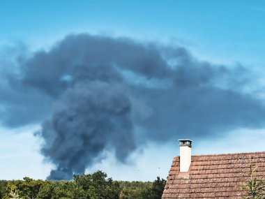 Yanan bir plastik geri dönüşüm yeri, gökyüzü mavi yaz gününde koyu siyah bir duman yığınına neden olur. Tehlike, keder. Terörist saldırı ya da patlama. Çevre felaketi