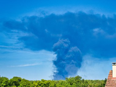 Yanan bir plastik geri dönüşüm yeri, gökyüzü mavi yaz gününde koyu siyah bir duman yığınına neden olur. Tehlike, keder. Terörist saldırı ya da patlama. Çevre felaketi
