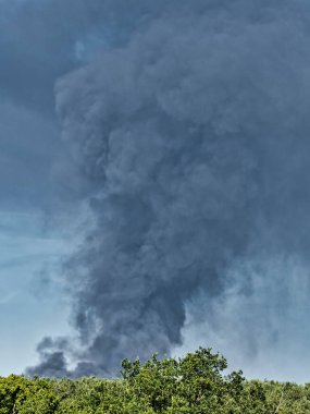 Yanan bir plastik geri dönüşüm yeri, gökyüzü mavi yaz gününde koyu siyah bir duman yığınına neden olur. Tehlike, keder. Terörist saldırı ya da patlama. Çevre felaketi