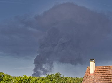 Yanan bir plastik geri dönüşüm yeri, gökyüzü mavi yaz gününde koyu siyah bir duman yığınına neden olur. Tehlike, keder. Terörist saldırı ya da patlama. Çevre felaketi