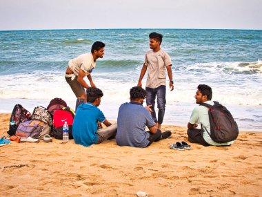 PUDUCHERRY, İNDİA - Aralık 2018. Denizde banyo yapmadan önce plajda kimliği belirsiz öğrenci grubu konuşuyor.