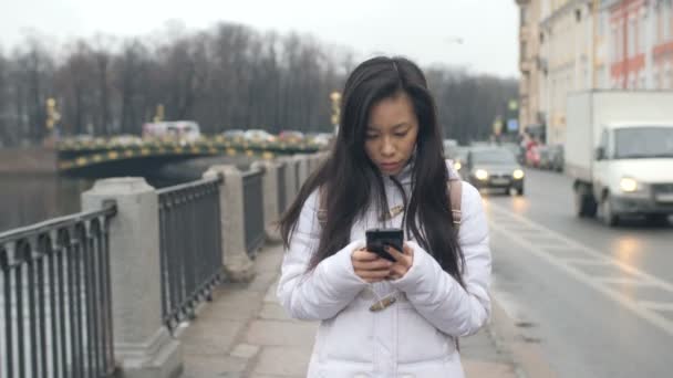 Junge asiatische Frau zu Fuß SMS-Handy Smartphone in der Stadt — Stockvideo