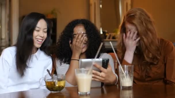 Многоэтническая группа девочек, смеющихся над телефоном, табличкой в кафе — стоковое видео