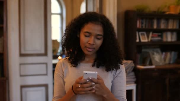 Femme noire afro-américaine entre dans le café en parlant au téléphone, souriant . — Video