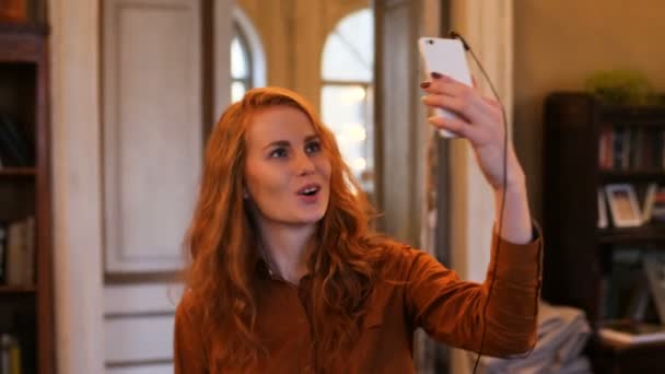 Jeune femme caucasienne aux cheveux rouges prenant Selfie au café — Video