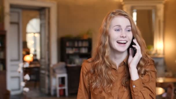 Feliz joven rojo pelo caucásico mujer hablando en el teléfono celular en café — Vídeos de Stock