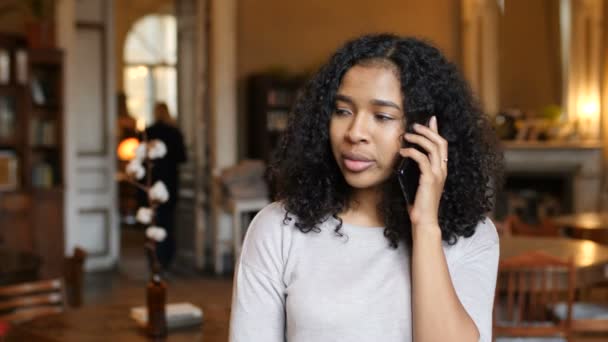 Молодая афро-американская чёрная женщина, разговаривающая по мобильному телефону в кафе — стоковое видео