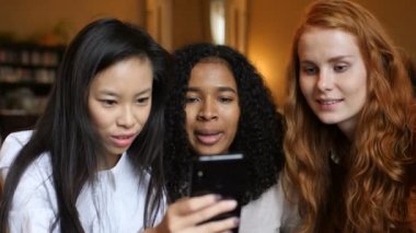 Çok etnik grup kızlar gülen bir telefon, bir tablet birlikte içinde bir Cafe