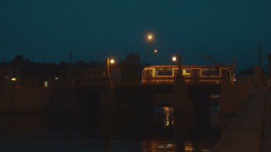 Eski şehirde köprü üzerinde gece şehir tramvay sürmek. Köprüdeki ışıklar Sarı renkte parlıyor.