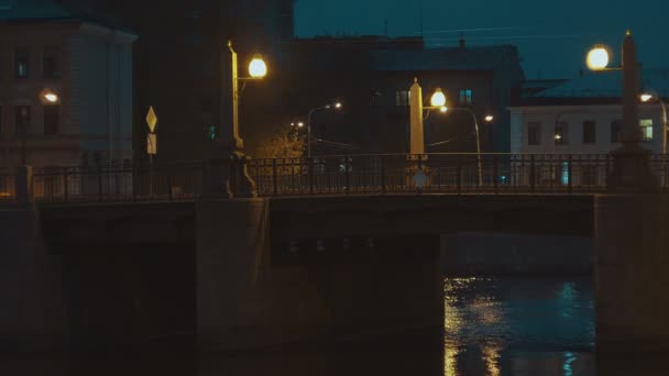 Το τραμ της πόλης ταξιδεύει τη νύχτα στη γέφυρα της παλιάς πόλης. Φώτα στη γέφυρα λάμψη κίτρινο. — Αρχείο Βίντεο