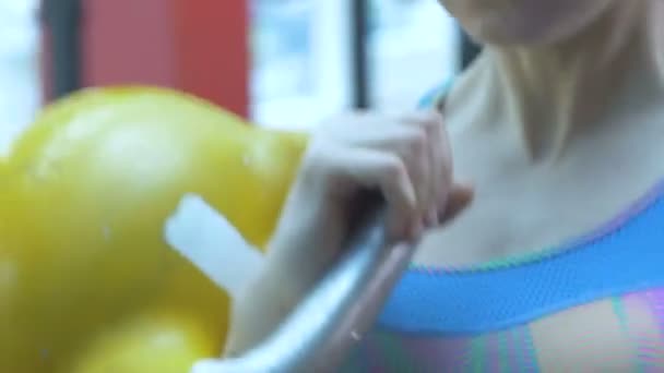Flicka i gymmet, lyfter metall vikter och rynkar pannan med ansträngning. — Stockvideo