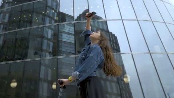 Cute tourist taking pictures of futuristic business center with smartphone camera. — Stock Video