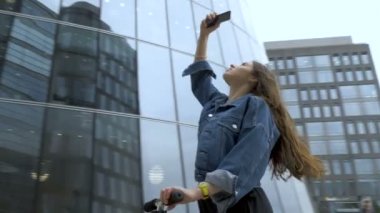 Sevimli turist akıllı telefon kamera ile fütüristik iş merkezinin fotoğraf çekmek.