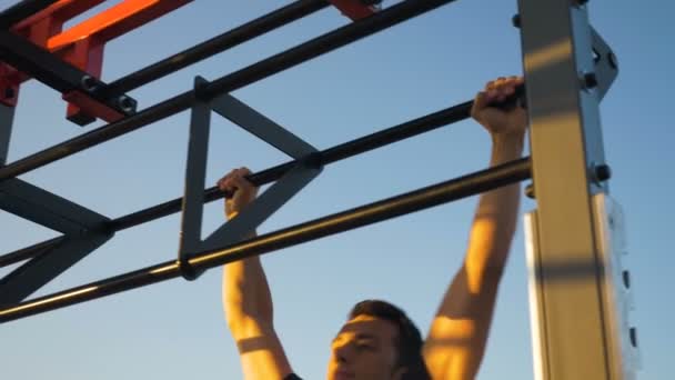 Молодой спортсмен делает упражнения на барной стойке и лестнице — стоковое видео