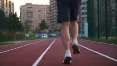 Gün doğumunda koşmak için pistte koşan bir atlet.