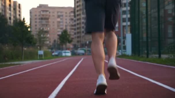 Sportowiec biegnie po torze do biegania o wschodzie słońca. — Wideo stockowe
