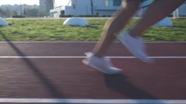 Gün doğumunda koşmak için pistte koşan bir atlet.