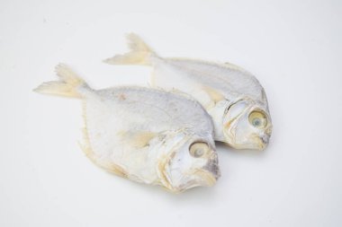 Beyaz bir arka plana yerleştirilmiş iki kurutulmuş balık görülebilir doku ve detaylara sahip korunmuş deniz ürünleri sergileniyor.