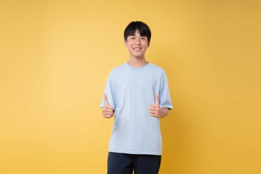 Sarı bir arkaplan önünde gülümseyen bir şahıs, özgüvenini gösteriyor.