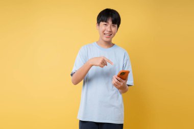 Genç insan, enerji dolu canlı sarı bir zemin karşısında cep telefonuna gülümser ve el kol hareketi yapar.