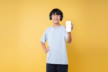 Kulaklık takan ve sarı ekranlı akıllı telefonu gösteren mutlu bir genç.