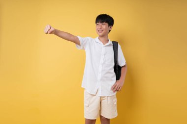 Sırt çantalı neşeli genç bir öğrenci parlak sarı bir arka plana karşı iyimser.