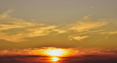 Ateş kırmızısı ve kül grisi tonları ile sihirli alacakaranlık gökyüzü güneş ışığı çarpıcı bir kontrastta dokulu fırtına bulutlarının arkasına saklanır.