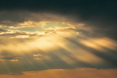 Günbatımında gökyüzü rüya gibi pastel ateşle parlıyor, bulutların arkasında sıcak ve serin tonlarla harmanlanıyor büyülü bir kompozisyonda.