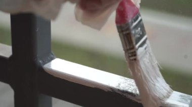 Beyaz boyayla metal yapıları fırçayla boyamak.