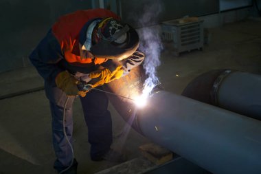 A professional welder works with manual arc welding. Welds pipe to pipe DN250. Pipeline butt weld.                         
