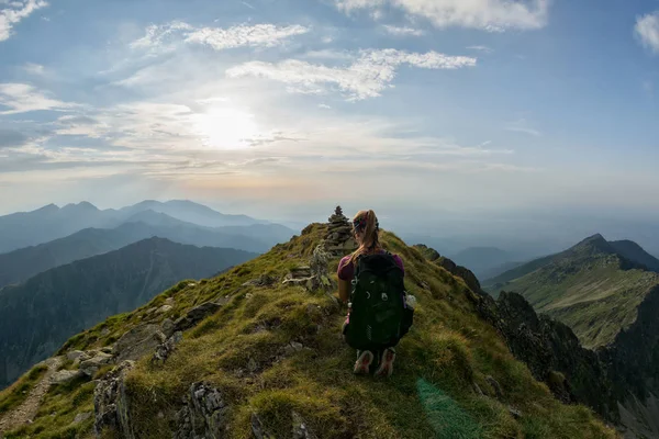一个徒步旅行的女孩在阳光下的山顶上休息 — 图库照片