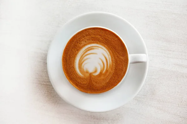 Kalp üzerinde süt köpüğü ile beyaz fincan kapuçino. Yukarıdan görüntülemek.