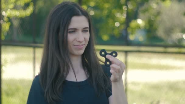 Joven mujer girando un hilandero en su mano al aire libre. Chica spinning spinner — Vídeos de Stock