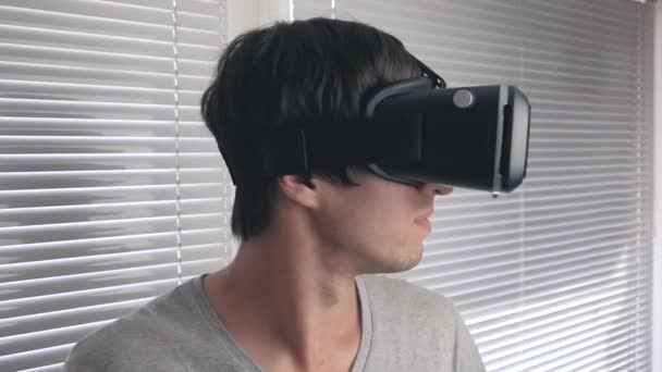 Junger Mann, der sein vr-Headset benutzt, um das 360-Video im Hintergrund im Büro anzusehen. Nahaufnahme. — Stockvideo