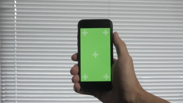 Gros plan des mains masculines touchant le smartphone au bureau sur le fond des stores. Écran vert Chroma Key . — Video