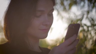 bir göl günbatımı bir arka plan üzerinde akıllı telefon kullanan genç oldukça esmer kadın