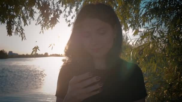 湖の夕日を背景に若いかなりブルネットの女性の肖像画 — ストック動画