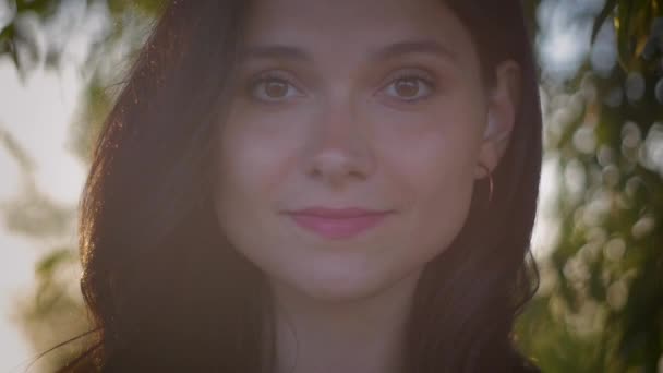 Retrato de una joven guapa morena sobre un fondo al atardecer en un lago — Vídeos de Stock