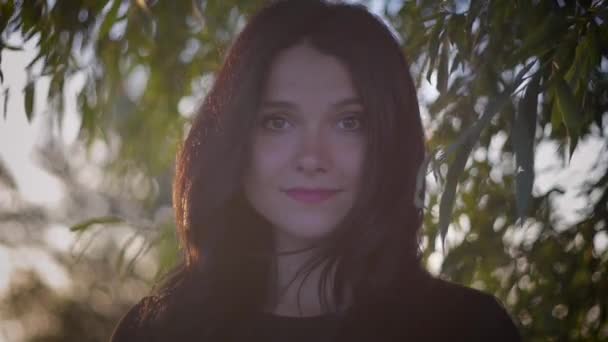 Portret van jonge mooie brunette vrouw op een zonsondergang achtergrond op een meer — Stockvideo