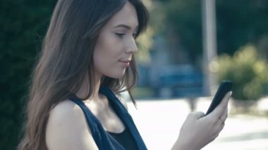 smartphone açık sokak arka plan kullanan genç güzel kadın portresi