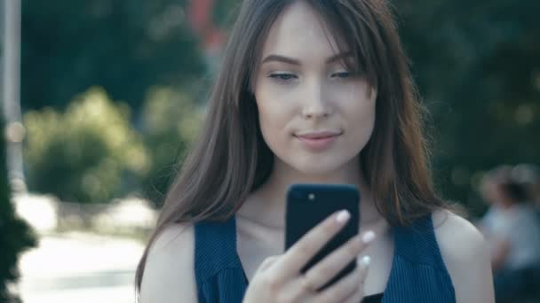 Портрет молодой красивой женщины с помощью смартфона на открытом воздухе на фоне улицы — стоковое видео
