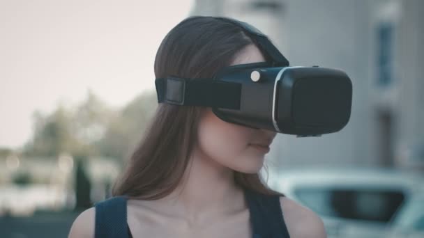 Primer plano retrato cara mujer atractiva cabeza mirando alrededor usando gafas VR en la calle. Chica consiguiendo expirience mientras usa auriculares de realidad virtual en verano al aire libre . — Vídeos de Stock
