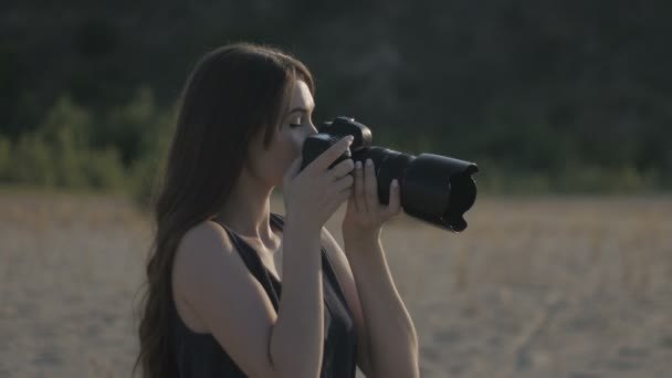 Jeune belle femme photographe avec l'appareil photo professionnelourdoor. Fille fait un tir et en regardant la photo sur la caméra — Video