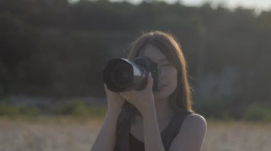 Genç güzel kadın fotoğrafçı profesyonel kamera ourdoor ile. Kız bir atış yapma ve fotoğraf fotoğraf makinesi üzerinde seyir