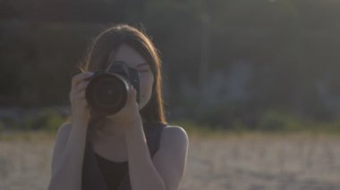 Genç güzel kadın fotoğrafçı profesyonel kamera ourdoor ile. Kız bir atış yapma ve fotoğraf fotoğraf makinesi üzerinde seyir