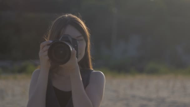 Joven hermosa fotógrafa con la cámara profesional ourdoor. Chica está haciendo una toma y mirando la foto en la cámara — Vídeo de stock