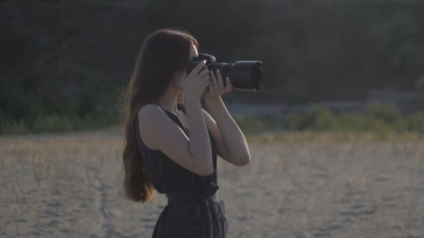 Φωτορεπόρτερ γυναίκα παίρνει μια φωτογραφία της φύσης χρησιμοποιώντας μια επαγγελματική φωτογραφική μηχανή. Κορίτσι κάνει έναν πυροβολισμό και κοιτάζοντας τη φωτογραφία στη φωτογραφική μηχανή — Αρχείο Βίντεο